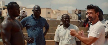 Man speaking with Senegalese wrestlers